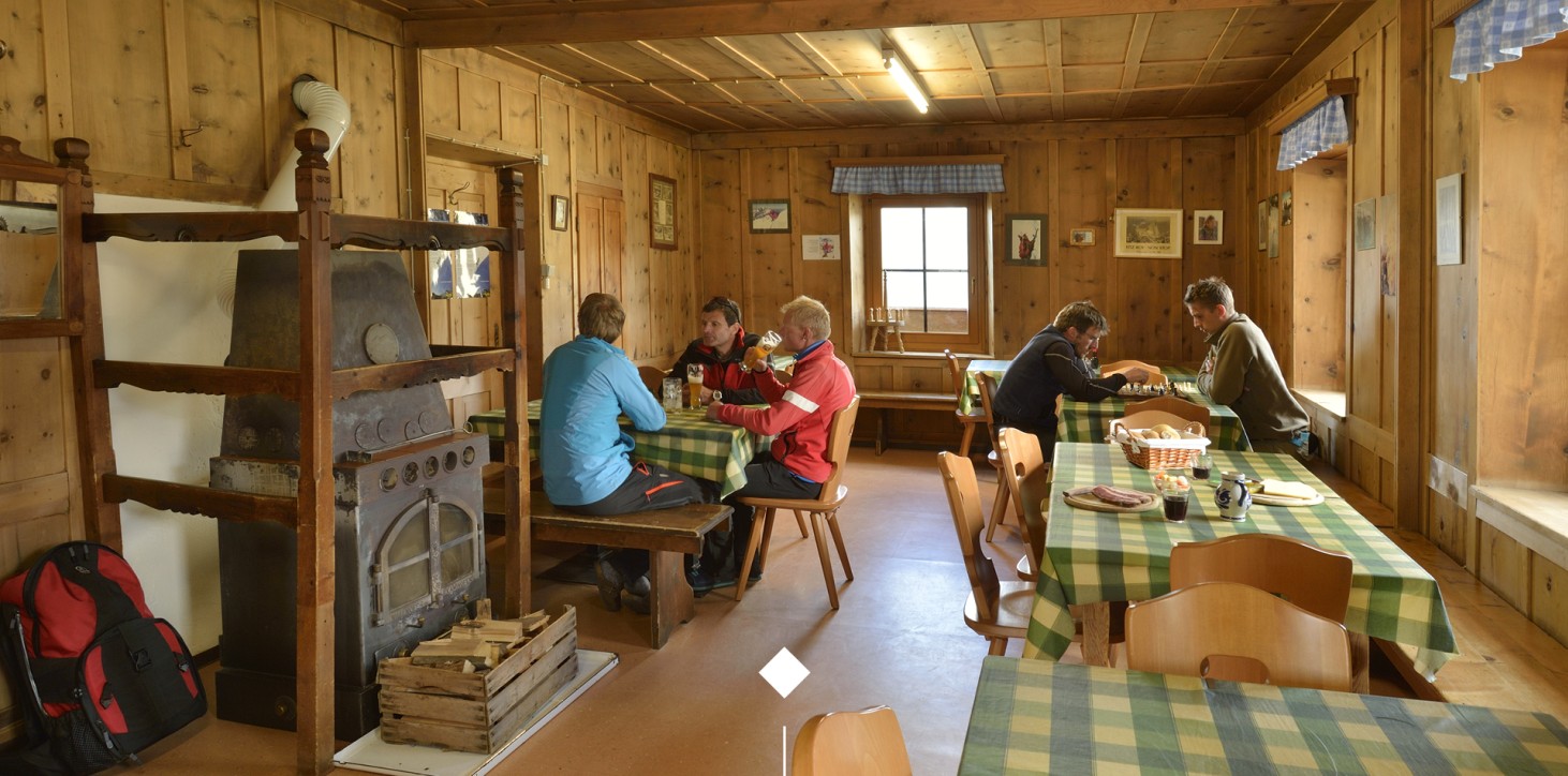 Escursionisti che si ritrovano in modo conviviale nella stanza dell o rifugio Coston
