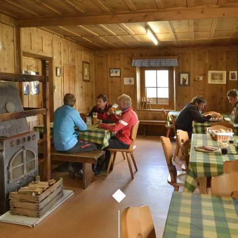 Rifugio Coston: Accogliente sala con stufa a legna per gli ospiti. Escursionisti che si ritrovano in modo conviviale nella stanza dell o rifugio Coston