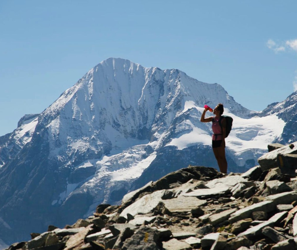 Rifugio Coston: Un'esperienza di montagna con aria fresca estiva ed emozioni intense. Un'escursionista mentre beve lungo il sentiero di pietra di fronte all'Ortles.
