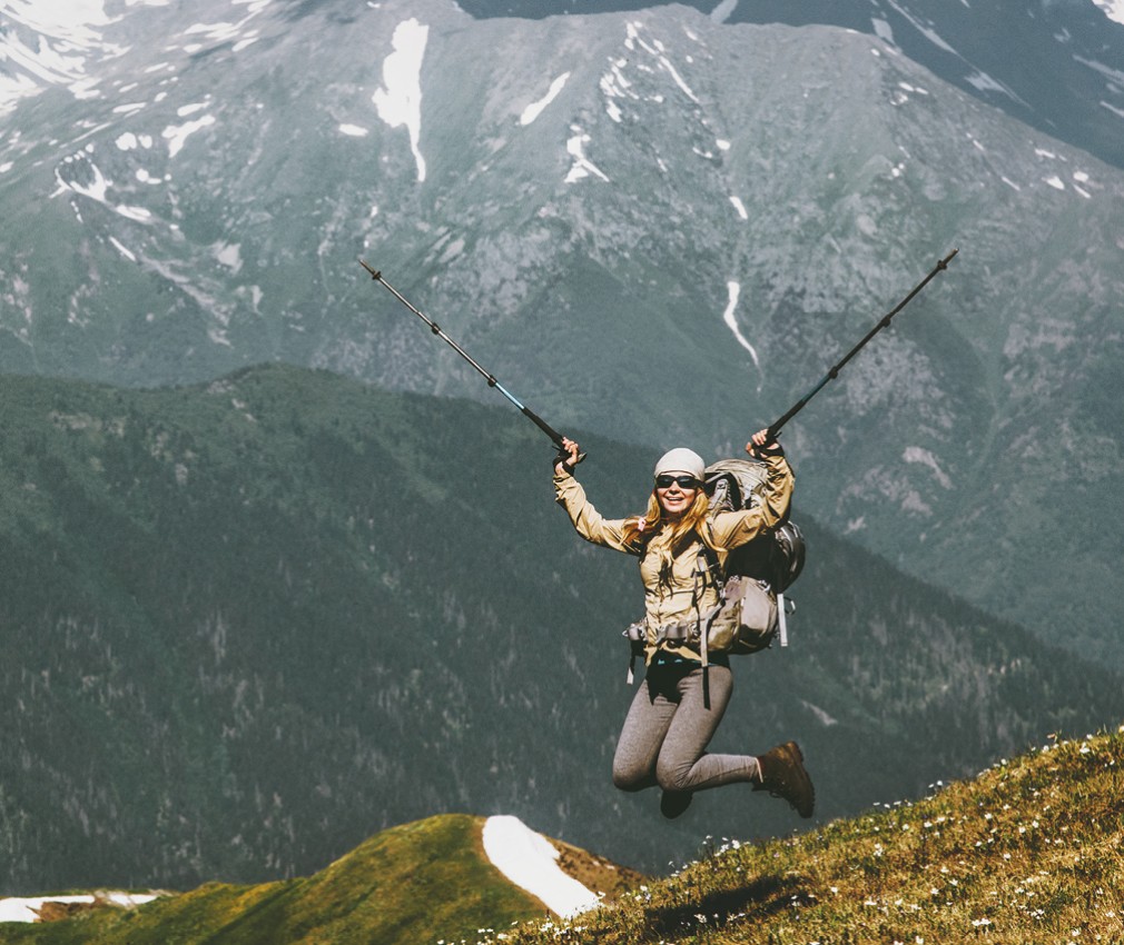 Una felice alpinista con uno zaino da trekking completamente carico.