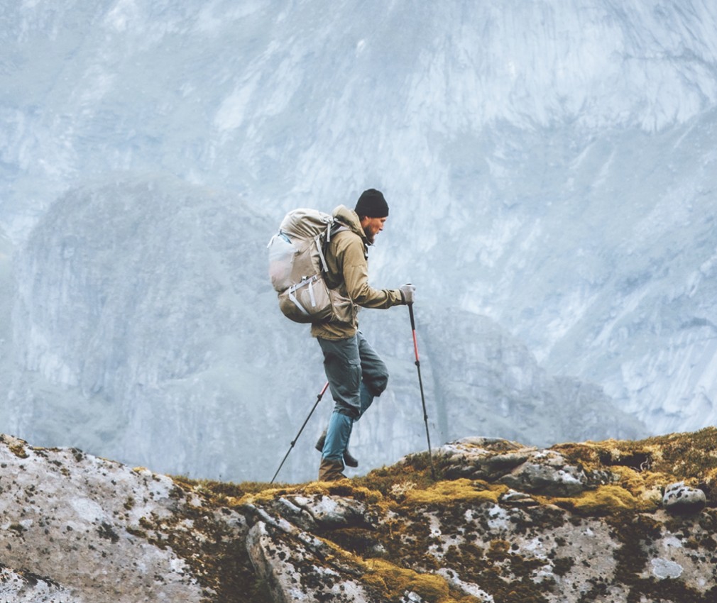 Un alpinista con bastoncini da trekking e uno zaino da escursionismo in montagna.
